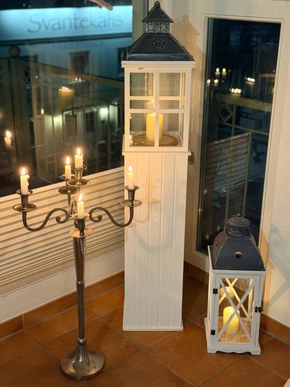 Weiße Laterne, Standleuchter mit Kerzen und Windlicht vor dem Fenster