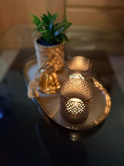 Windlichter und Grünpflanze auf einem goldenen Tablett